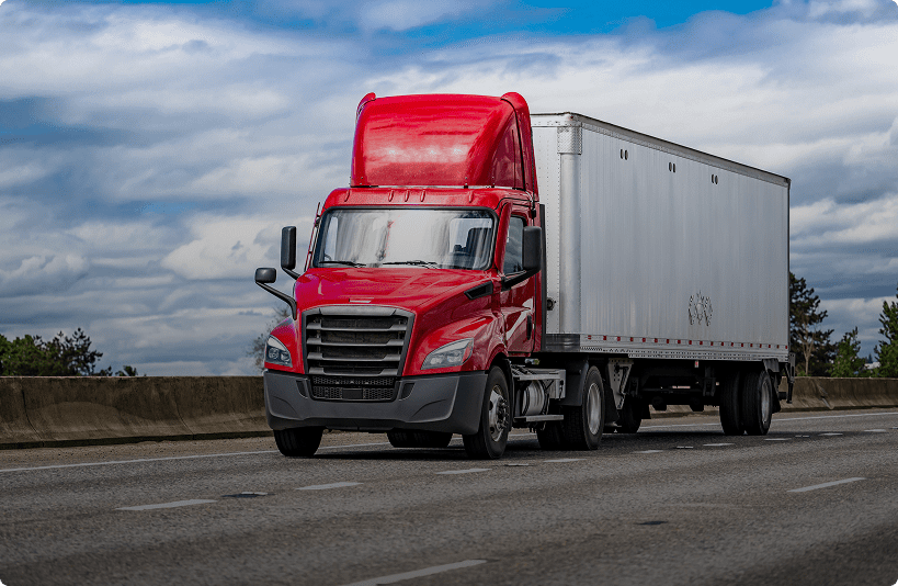 Red truck driving on a highway road.
